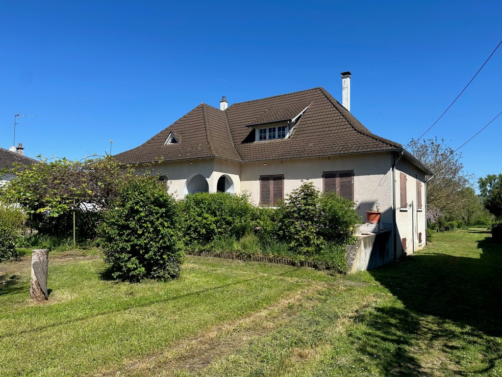 A house surrounded by greenery and a clear blue sky, reflecting a serene and natural environment.